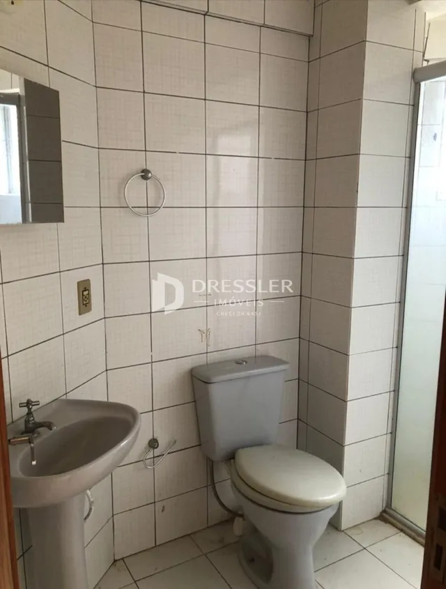 Foto de um banheiro com azulejos brancos e louças sanitárias.