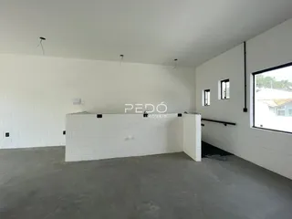 Ambiente interno de uma residência com paredes brancas e piso de concreto.