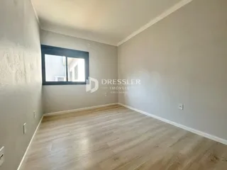 Ambiente interno de uma sala com piso de madeira clara e paredes neutras.