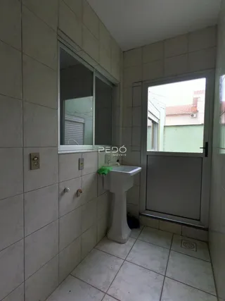 Foto do interior de um banheiro com piso de cerâmica e azulejos claros.