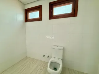 A foto mostra o interior de um banheiro com paredes brancas e piso claro.