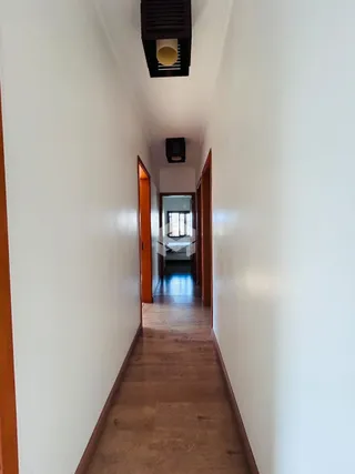 Corredor interno de uma residência com piso de madeira e paredes brancas.