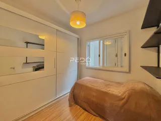 Quarto com armário embutido e piso de madeira clara.