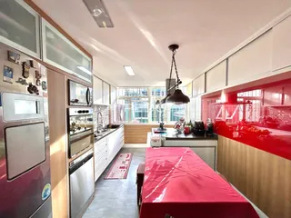 Vista da cozinha moderna com armários brancos e detalhes em vermelho.