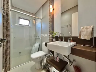 Banheiro moderno com box de vidro e louças brancas.