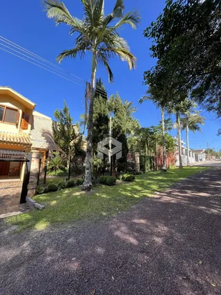 Vista da fachada de uma residência em Lajeado, Brasil, com jardim e árvores.