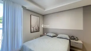 Quarto com cama e cortinas brancas.