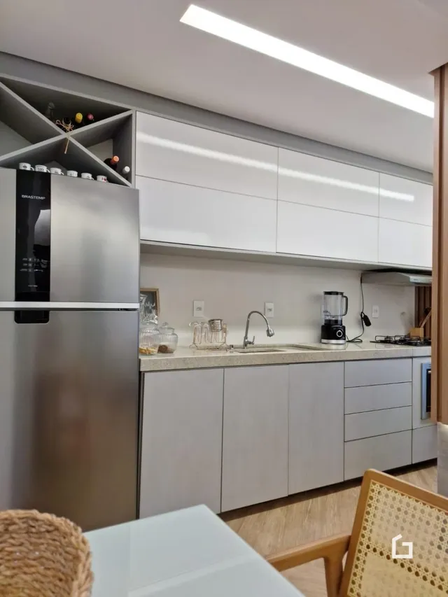 Cozinha moderna com armários brancos e eletrodomésticos de aço inoxidável.