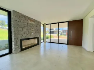 Sala de estar com parede de pedra e grandes portas de vidro que dão para o exterior.