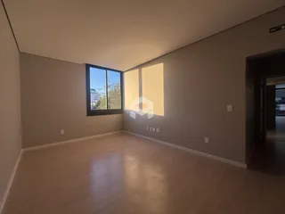 Ambiente interno de uma sala com piso de madeira clara e grande janela.