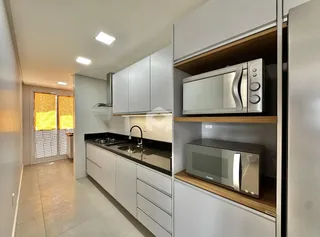 Vista da cozinha moderna com armários brancos e bancadas escuras.
