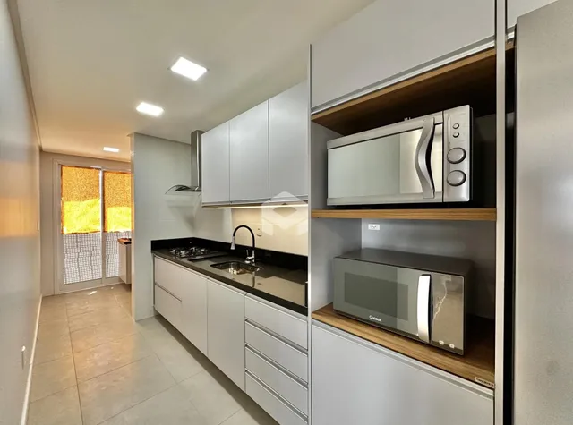 Vista da cozinha moderna com armários brancos e bancadas escuras.