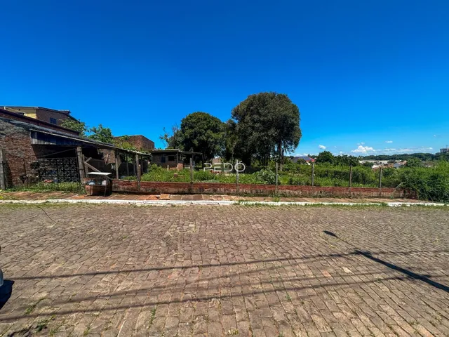 Vista externa do terreno com muro de tijolos e pavimento de paralelepípedos.