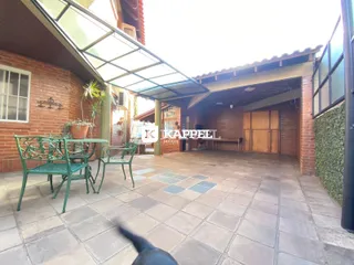 Área externa coberta com mesa e cadeiras de ferro verde.