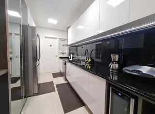 Cozinha moderna com armários brancos e bancadas escuras.