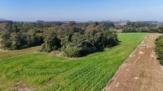 Vista aérea de uma área rural com campos verdes e vegetação densa.
