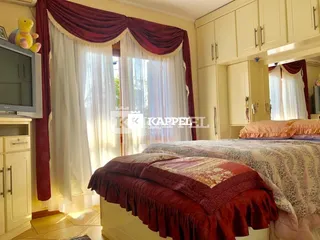 Quarto com cama e cortinas em ambiente interno.