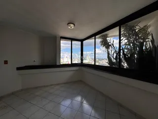 A sala possui grandes janelas com vista para a paisagem urbana.