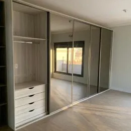 Vista interna de um corredor com paredes espelhadas e piso de madeira.