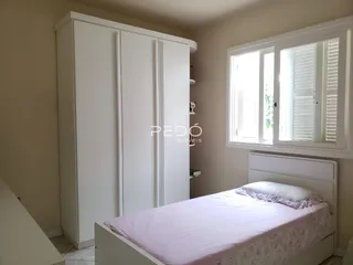 Quarto com guarda-roupas branco e cama em ambiente claro.