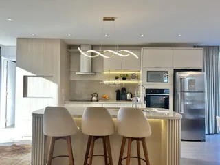 Uma cozinha moderna com ilha e armários brancos em um imóvel no Brasil.