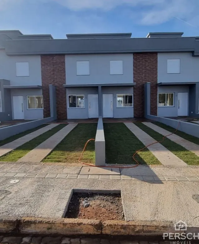 Fachada de uma casa residencial moderna com revestimento de tijolo aparente e paisagismo frontal.