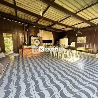 Uma sala ampla com piso de azulejos pretos e brancos e lareira de tijolos aparentes.