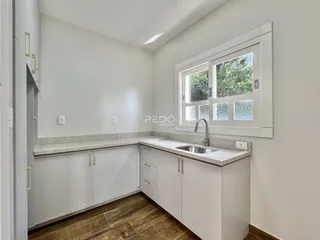 Foto de uma cozinha com armários brancos e piso de madeira em Lajeado.