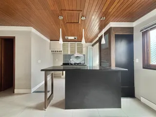 Cozinha moderna com ilha e teto de madeira em um imóvel no Brasil.