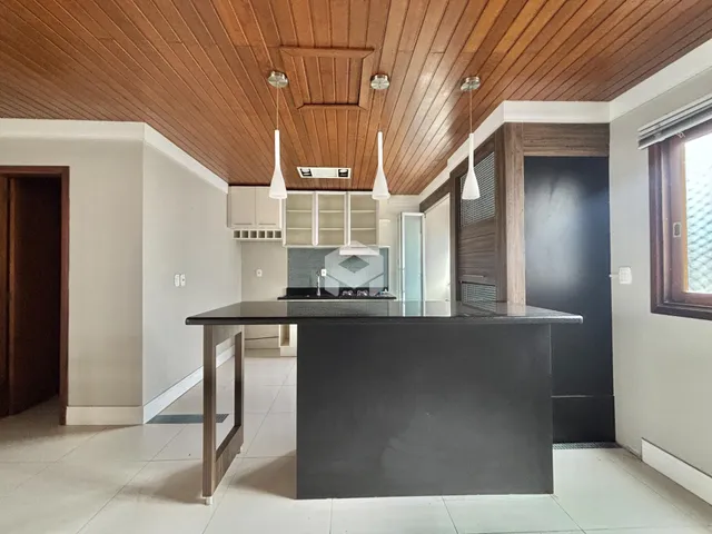 Cozinha moderna com ilha e teto de madeira em um imóvel no Brasil.