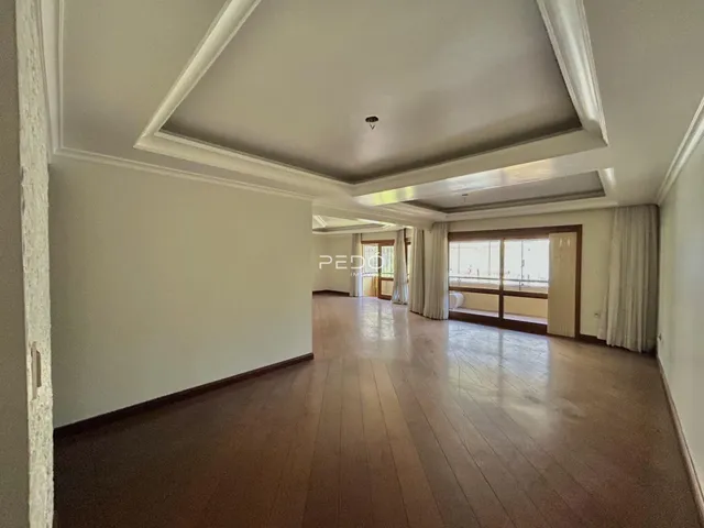 Interior de um corredor com piso de madeira e molduras brancas.