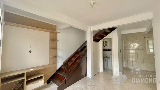Hall de entrada com escadaria de madeira e revestimento de piso cerâmico.