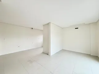 Ambiente interno de uma sala ampla e clara com piso de cerâmica.