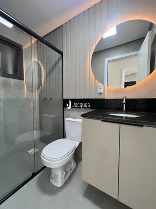 Foto de um banheiro moderno com box de vidro e louças brancas.