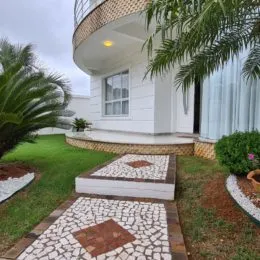 Fachada de uma residência com paisagismo e calçada de pedras.