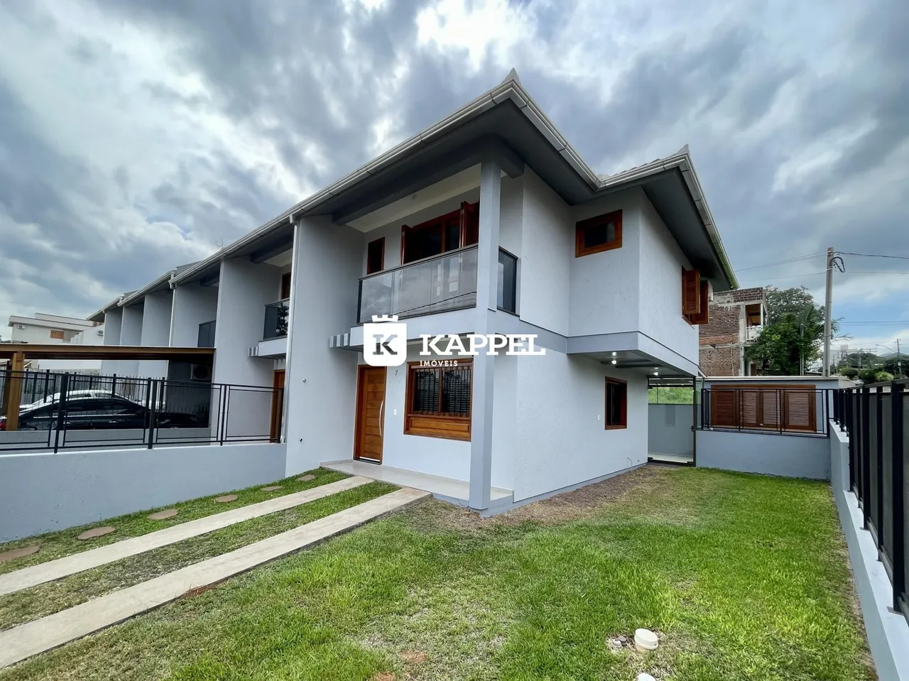 Fachada de uma casa residencial em Lajeado, Brasil, com jardim frontal e varanda no andar superior.