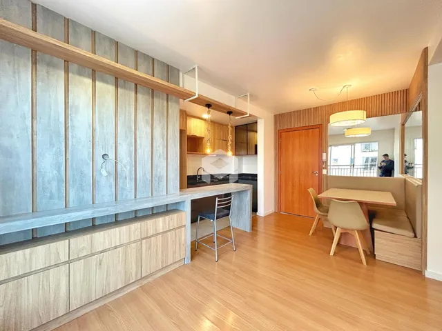 Ambiente interno de uma sala de estar com piso de madeira clara e bancada de cozinha.