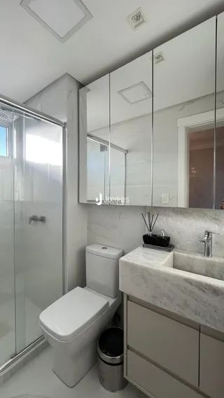 Banheiro moderno com box de vidro e bancada de mármore.