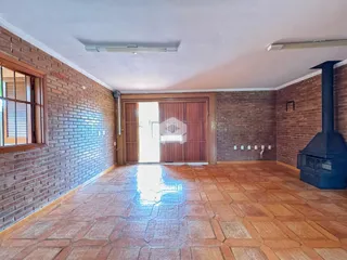 Imagem de uma sala com paredes de tijolo aparente e piso de cerâmica.