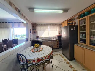 Uma sala de jantar com mesa de madeira e janelas.