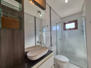 Foto de um banheiro moderno com box de vidro e louças brancas.