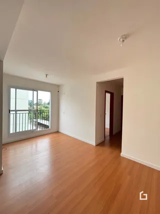 Vista interna de uma sala com piso de madeira clara e janela para a varanda.