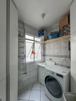 Interior de um ambiente com revestimento cerâmico e máquina de lavar roupa.