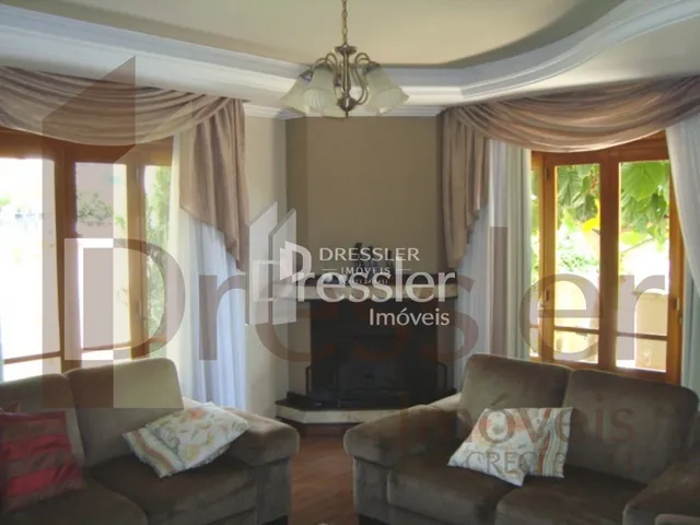 Sala de estar com janelas grandes e cortinas claras.
