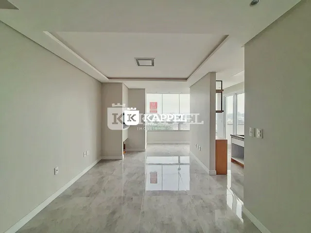 Hall de entrada amplo com piso de porcelanato claro e teto alto.