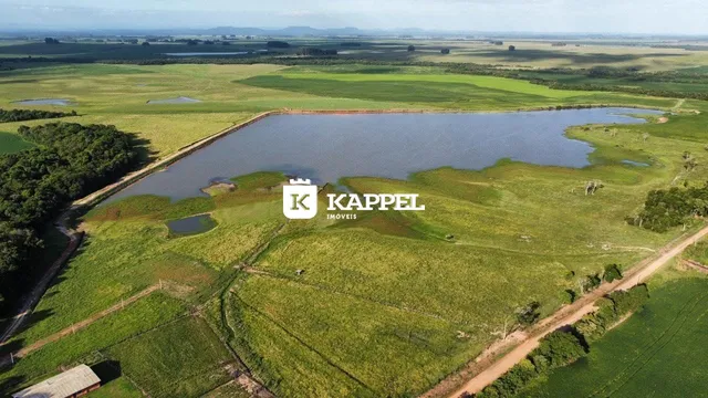 Vista aérea de uma propriedade rural com um lago e campos verdes.