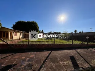 Vista externa de um pátio com piso de concreto e cerca.