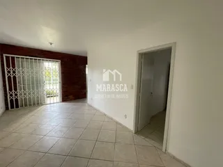 Hall de entrada com parede de tijolo aparente e porta de acesso ao interior.