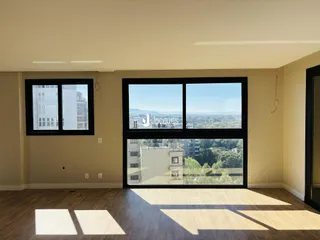 Sala de estar com piso de madeira e grande janela com vista para a paisagem.