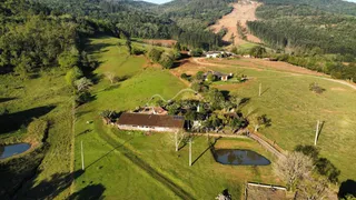 Vista aérea de uma residência em uma área rural com colinas verdes.